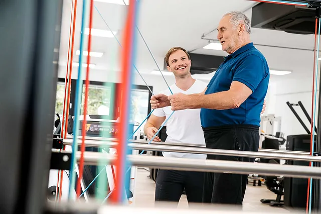 Trainer begleitet älteren Mann beim Gesundheitstraining im Fitnessstudio DAVID Fitness in Kirchdorf